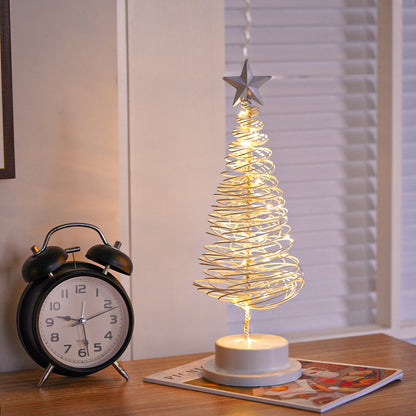 Decorative LED Christmas tree with star on a table next to a black alarm clock.