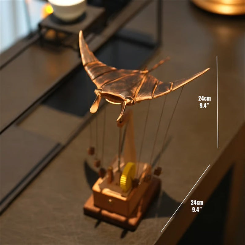 Decorative model of a manta ray on a reflective surface with measurements indicated.