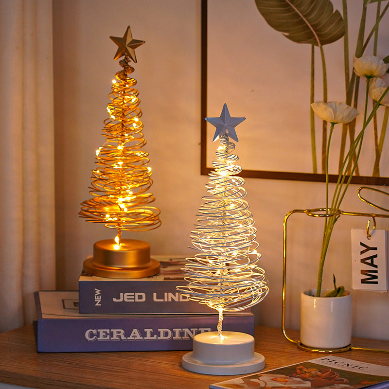 Two decorative LED trees on books with a vase of flowers and a calendar in the background.